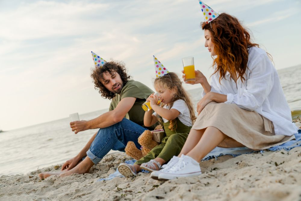 Una famiglia che ha prenotato un viaggio per il compleano e lo festeggia sulla spiaggia